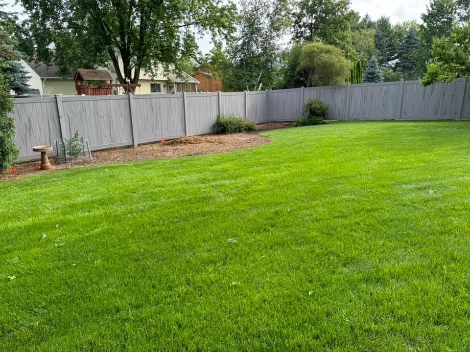 Green grassy backyard with a grey fence.