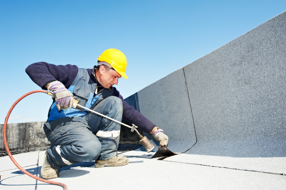 Worker in hard hat and safety vest installing roofing demonstrating TRO roofing benefits.