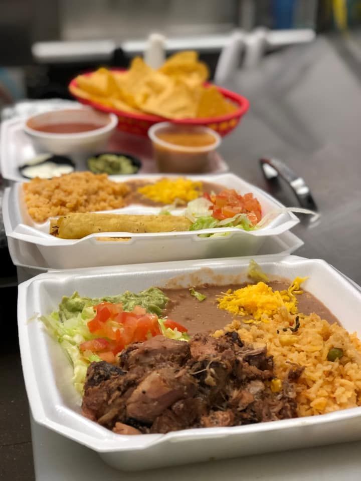 Two styrofoam containers filled with mexican food are sitting on a table.