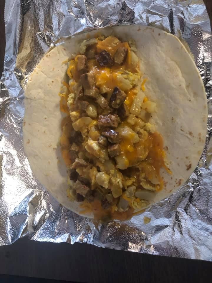 A burrito is sitting on top of a piece of tin foil.