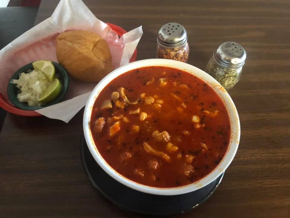 A bowl of soup sits on a table next to salt and pepper shakers