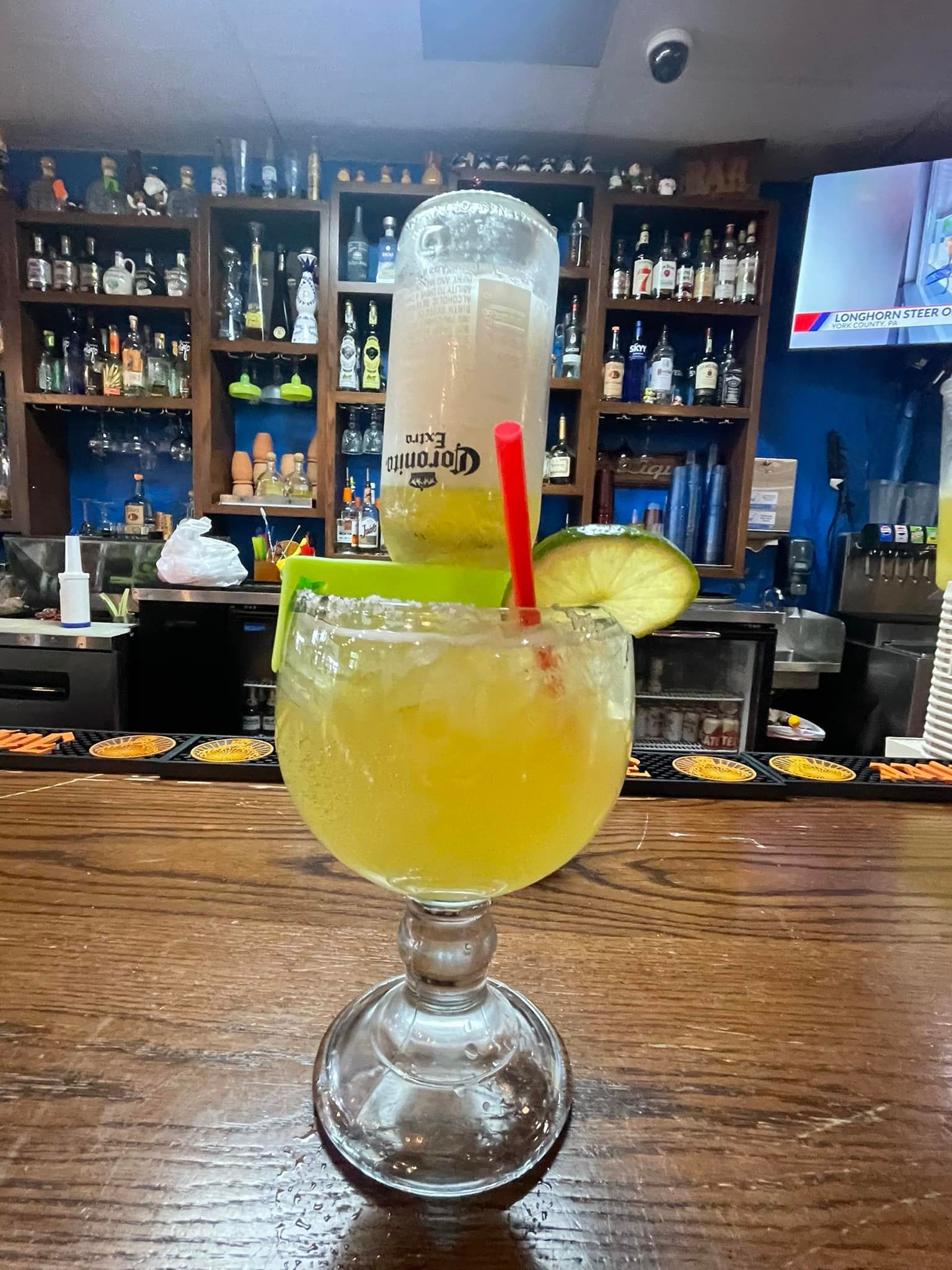 A margarita is sitting on a wooden table in a bar.