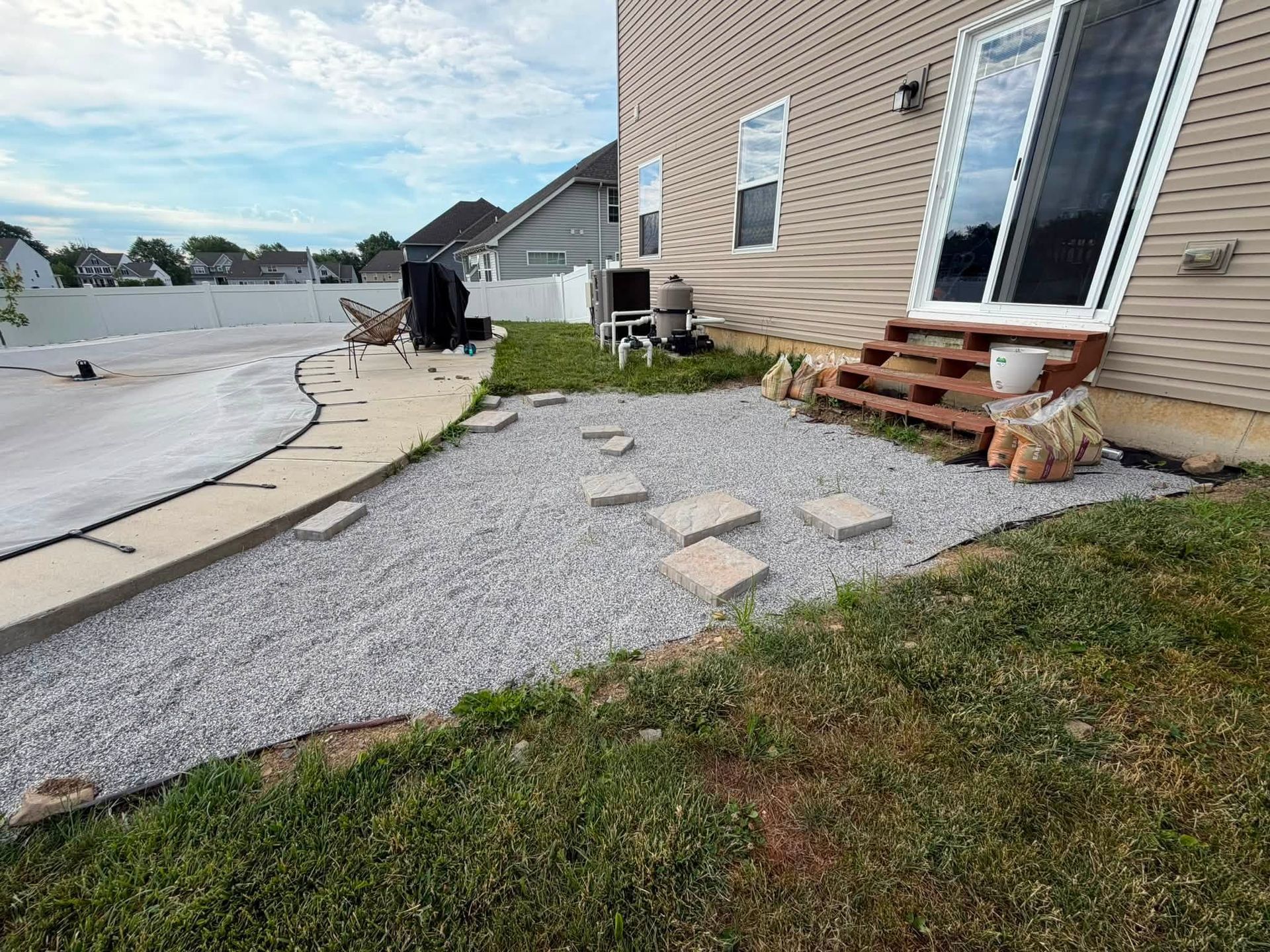 Backyard patio with gravel walkway, stepping stones, and a beige house exterior