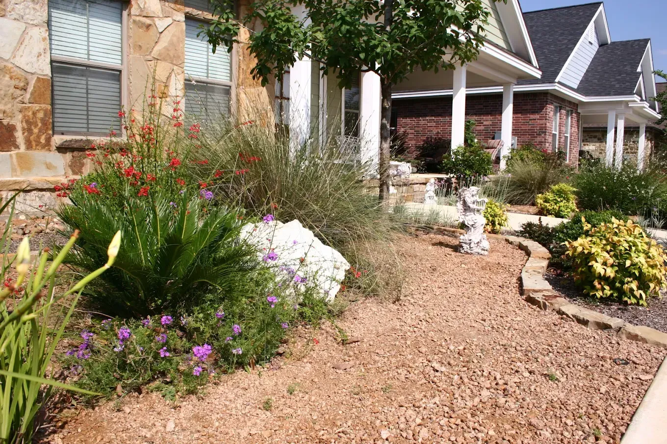 Exterior view of a house with a gravel pathway, landscaping, and a statue.