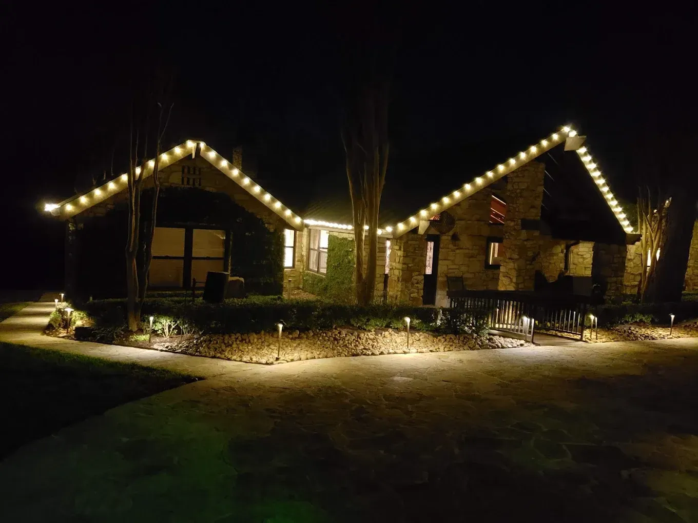 Stone cottages at night, illuminated with string lights and pathway lights.