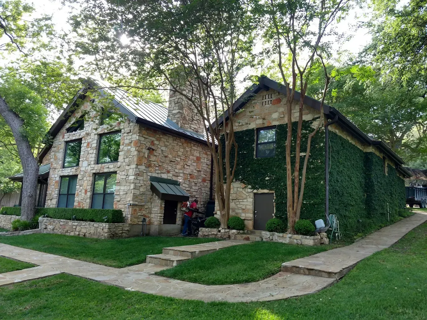 Stone buildings with green lawn and trees. One covered in ivy.