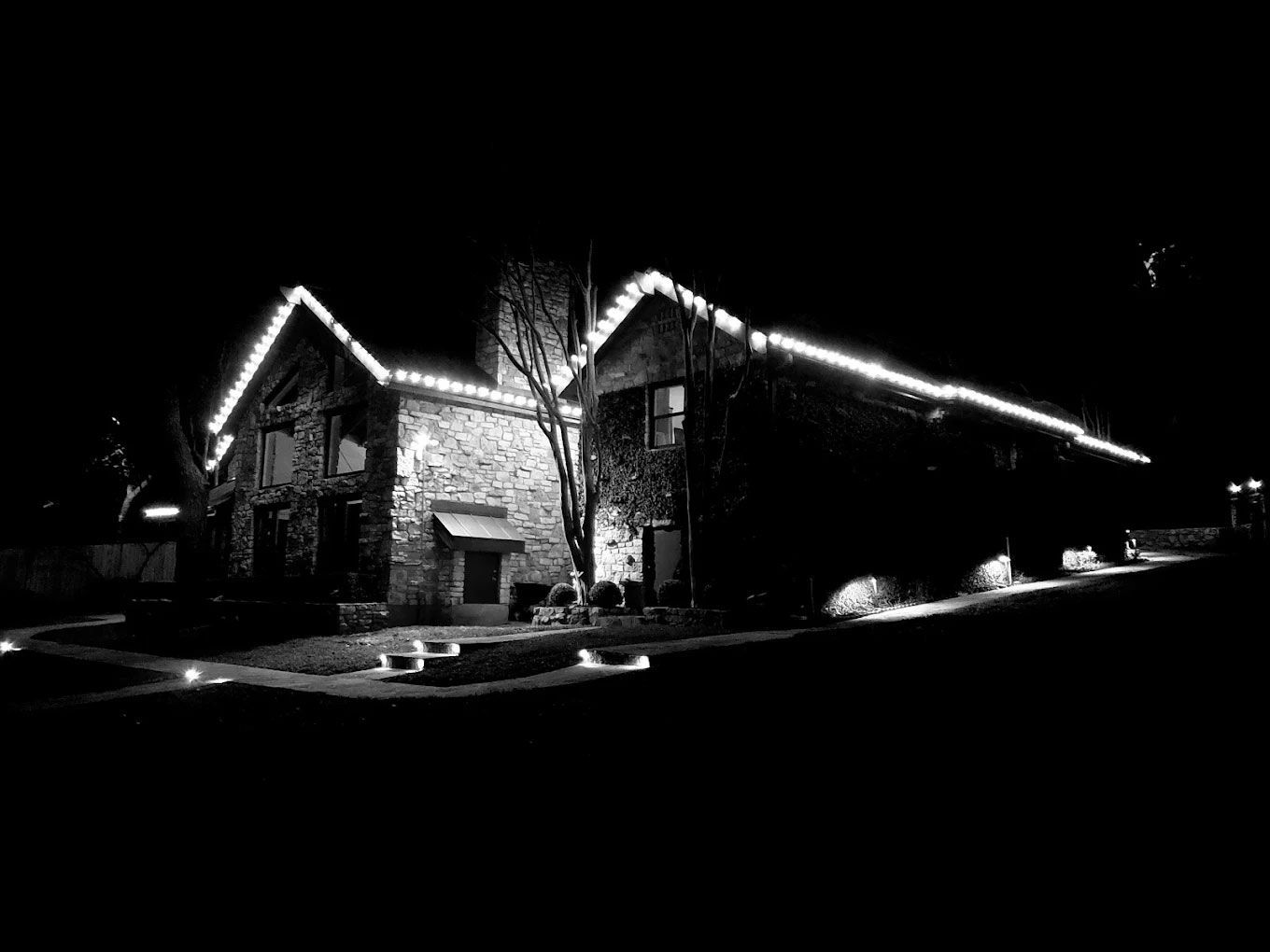 Stone building at night, illuminated by white lights along the rooflines and ground, against a black sky.