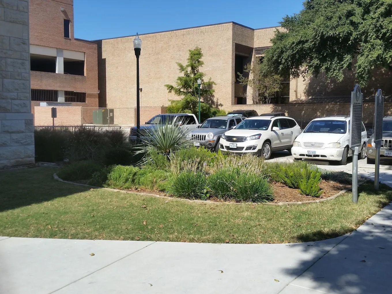 Cars parked near a building with landscaping. Sunny day.
