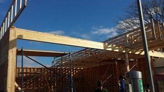 Construction of a wood-framed building against a blue sky.