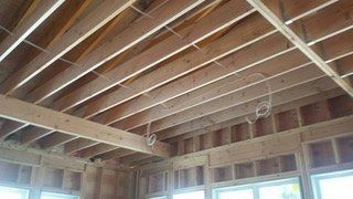 Wooden ceiling framework under construction, with exposed beams and wiring.