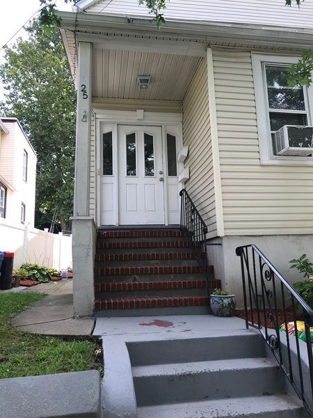 White house entrance with steps and a porch. The door has glass panels, and the house has light siding.