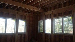 Interior view of a building under construction, showing wooden framing and window openings.