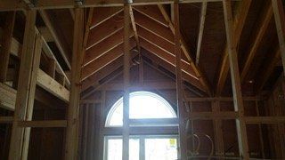 Wooden house frame construction with arched window.