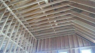 Interior view of a wooden house frame, showing the roof and walls under construction.