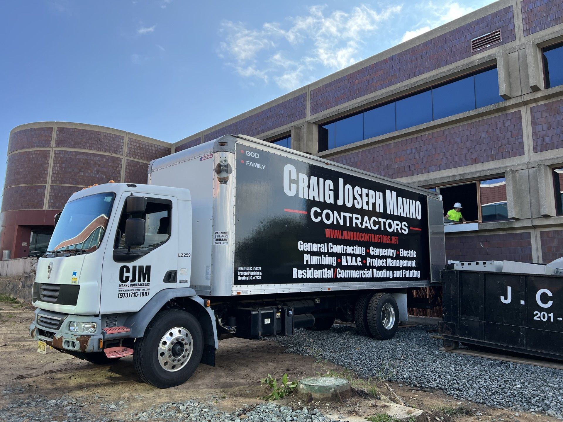 A white Craig Joseph Mayo Contractors truck parked at a construction site in front of a brick building.