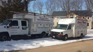 Two service trucks parked in snow, both with 