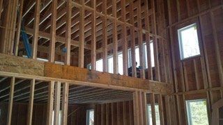 Interior wooden framing of a house under construction; windows in the walls.