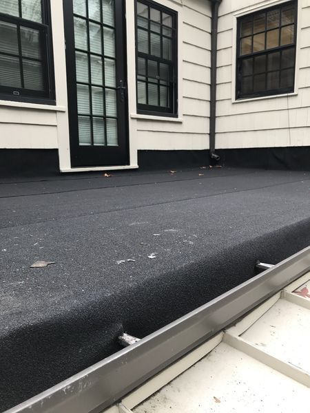 A flat black roof with dark windows and a door against white siding.