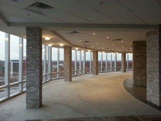 Curved room with stone columns, large windows, and an urban view.