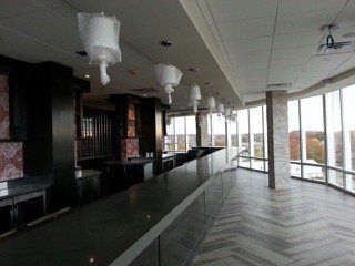 Interior bar with dark counter, large windows, and overhead lights covered in plastic.