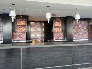Hotel front desk with dark wood counters and patterned wall panels.