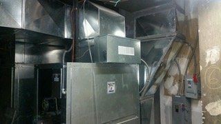 HVAC system with metal ductwork and control panel in an unfinished room.