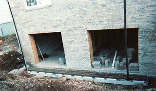 Brick building with two open garage door frames, foundation exposed during construction.