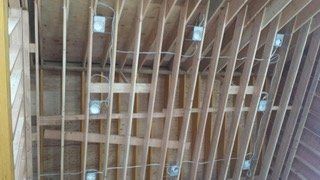 Wooden ceiling joists with electrical boxes and wiring installed.