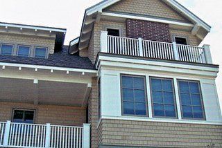Tan house with multiple levels, balconies with white railings, and windows.