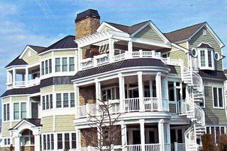 Multi-story house with light green siding, white trim, balconies, and a spiral staircase.
