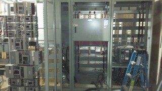 Electrical panel installation with exposed wiring and a ladder.