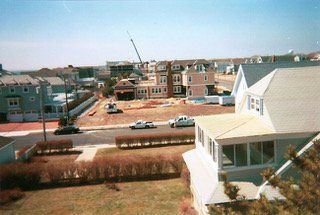 Coastal neighborhood with houses under construction; crane visible.