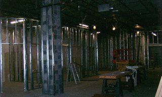 Interior view of a building under construction, metal framing exposed. Dim lighting, dark surroundings, empty space.