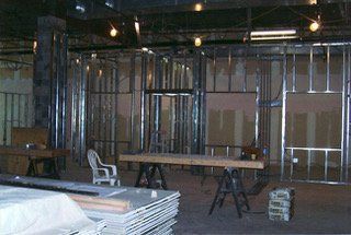 Interior of a building under construction, metal framing and drywall visible.