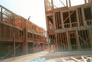 Wood frame construction of multi-story buildings; workers on roof.