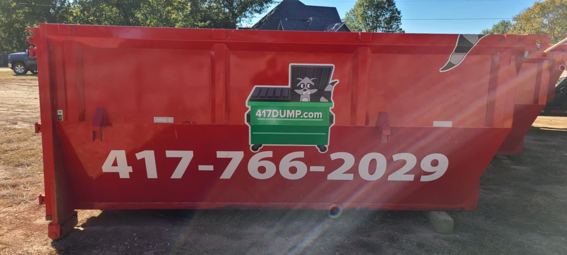 A red dumpster with the number 417-766-2029 on it