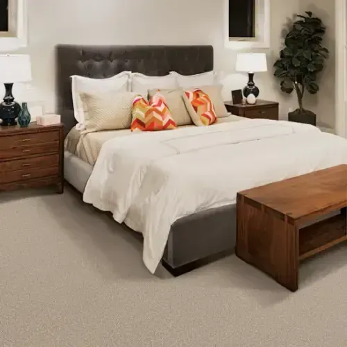 Bedroom with bed, nightstands, lamps, and decorative pillows on beige carpet.