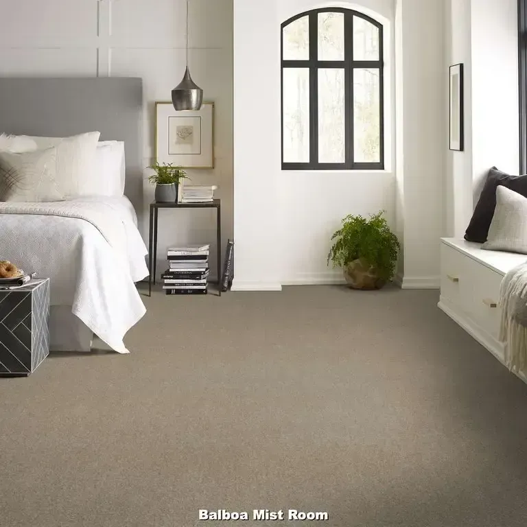 Bedroom with beige carpet, bed, window, side table, and bench.