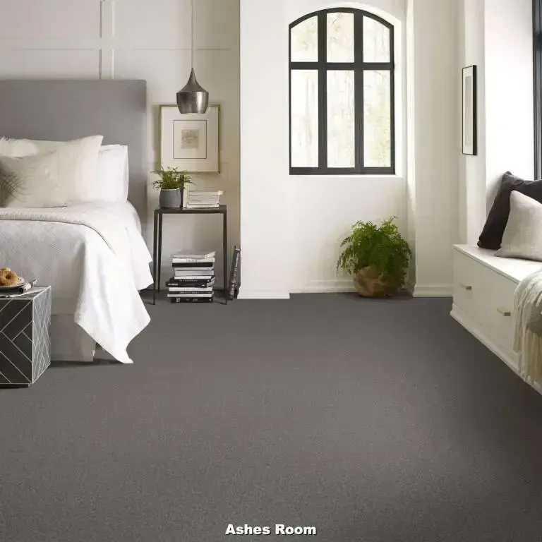Bedroom with gray carpet, bed, window, side table, and bench.