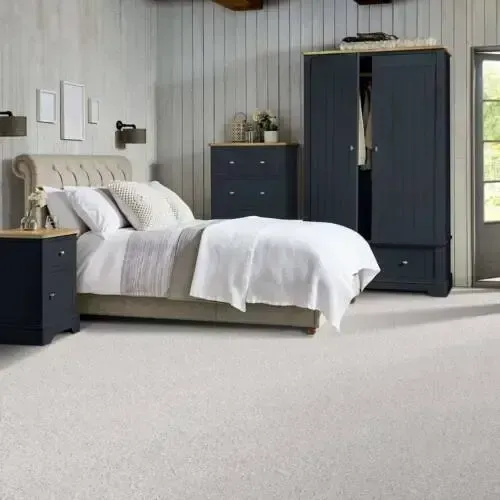 Bedroom with white carpet, bed, navy furniture, and door.
