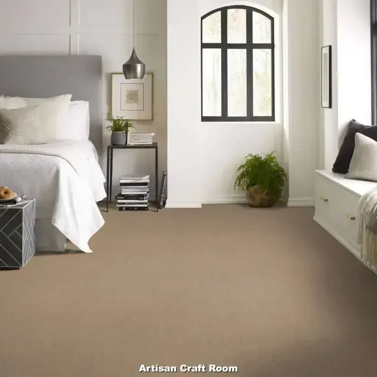 Bedroom with beige carpet, a bed, a window, and a small side table.