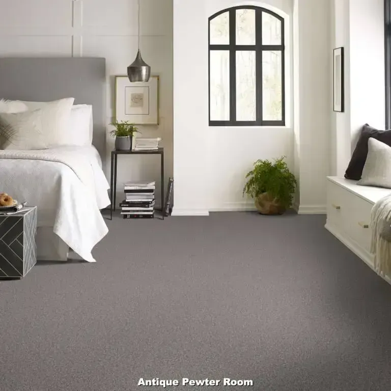 Bedroom with gray carpet, a bed with white bedding, and a window with a bench seat.
