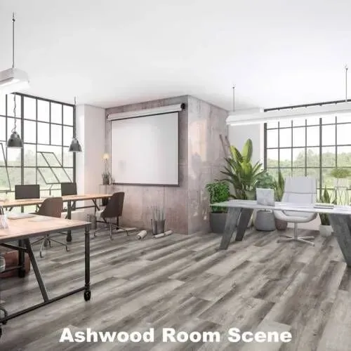 Office interior with wood floors, large windows, and desks. Includes plants, a projector screen, and overhead lights.