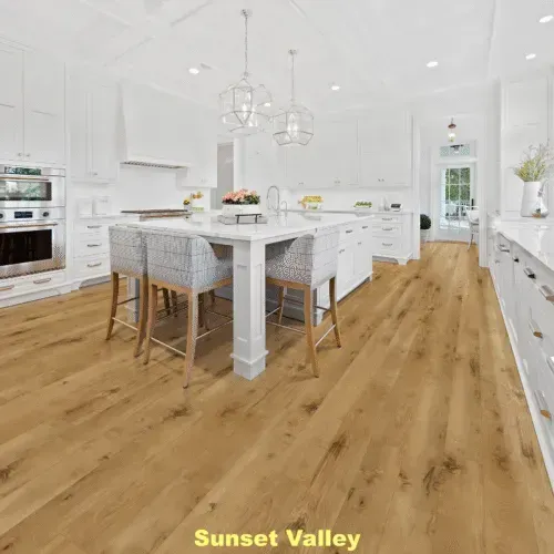 A bright white kitchen with a wooden floor and island with seating.