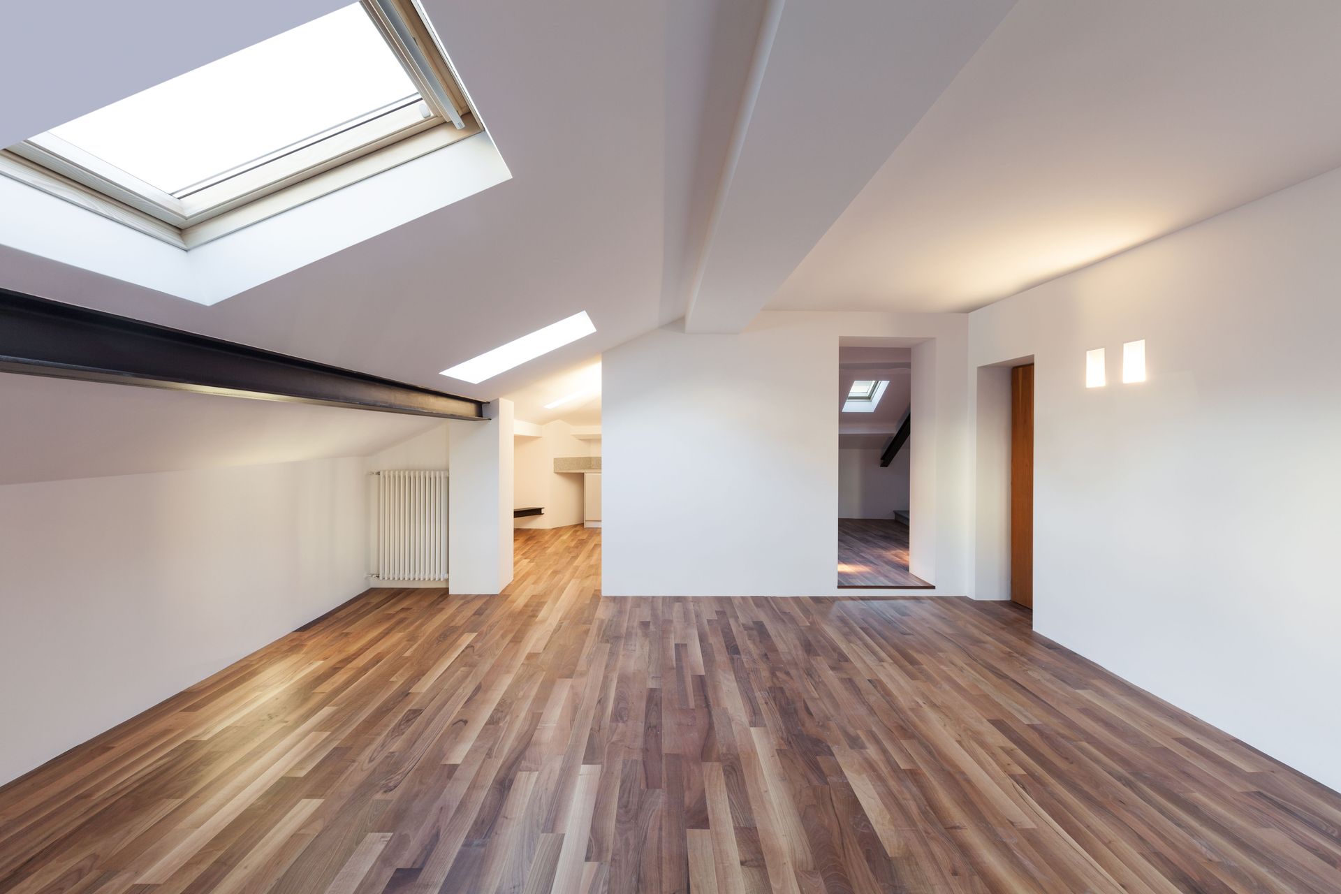 Empty modern loft with wood flooring, white walls, skylights, and recessed lighting