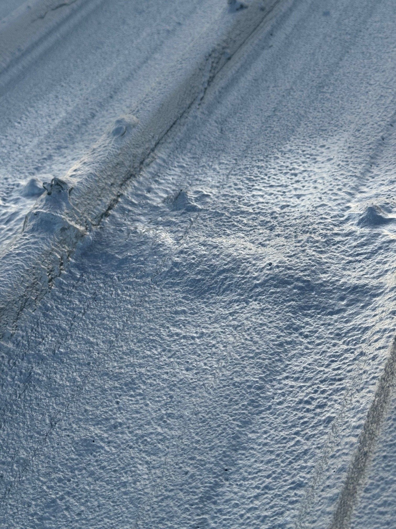Snow-covered textured surface with tire tracks and footprints