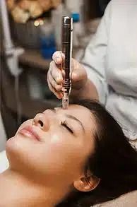 Beauty treatment with a facial wand applied to a relaxed woman lying down