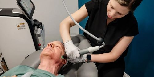 Dental treatment: clinician using a handheld device on a patient's open mouth in a clinic