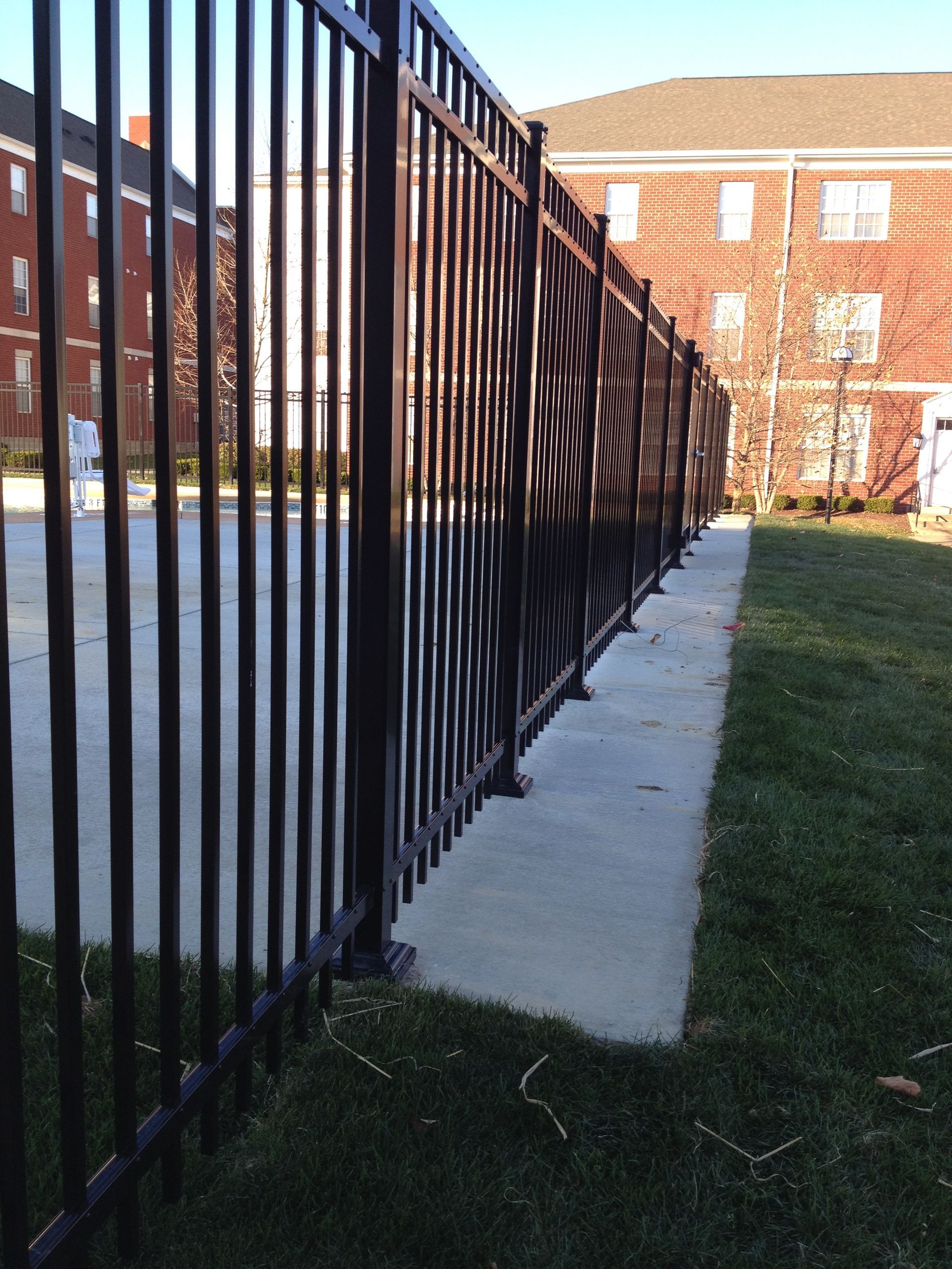 A fence with a brick building in the background