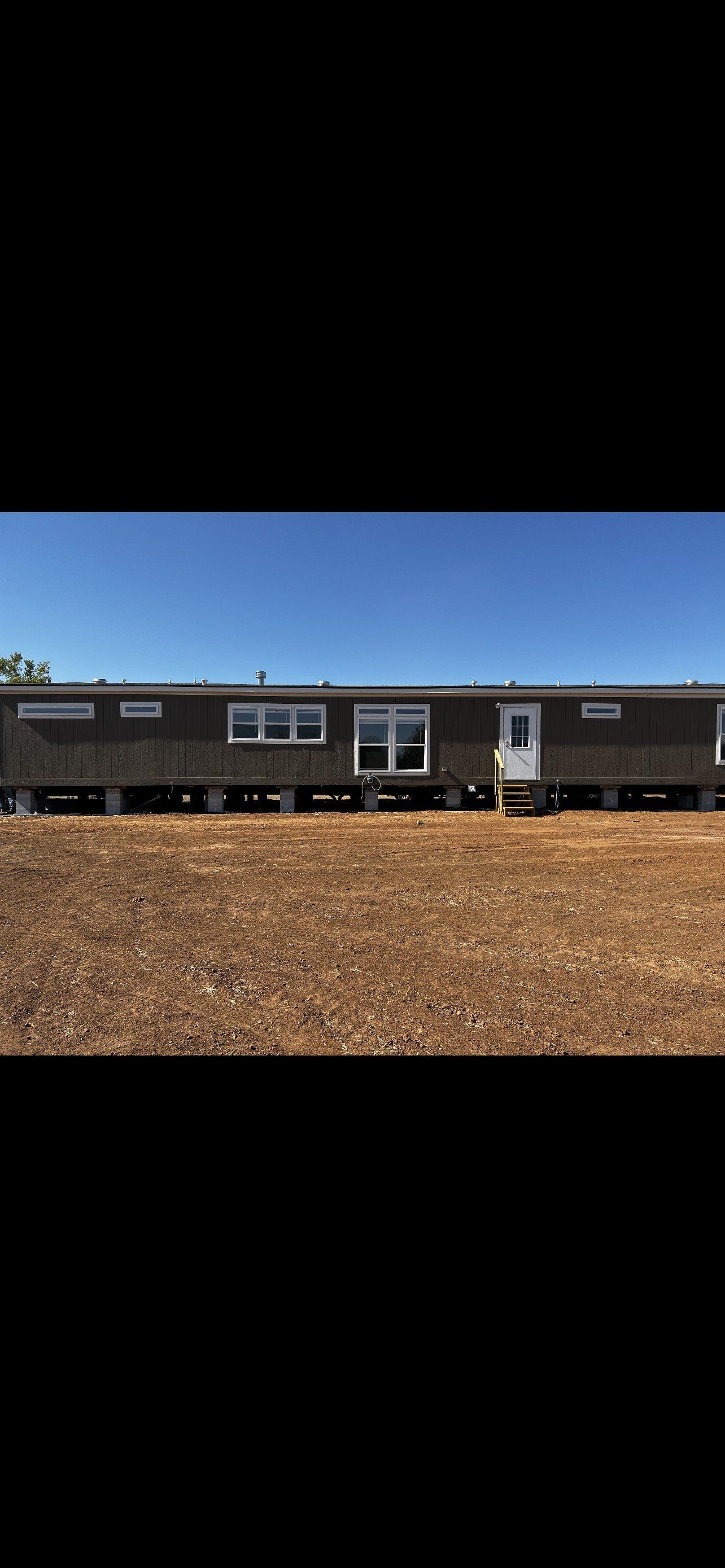 Gray mobile home on blocks.